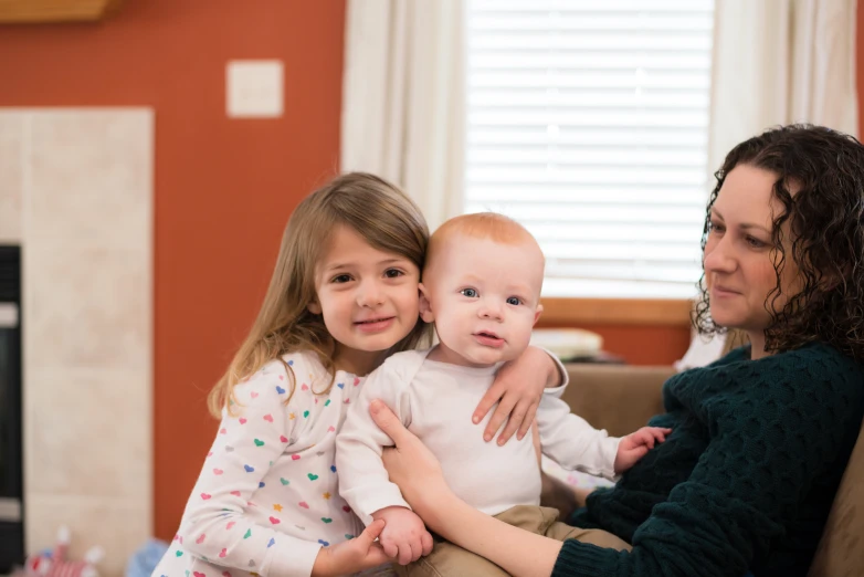 a woman holding a small child while her other mother is looking on