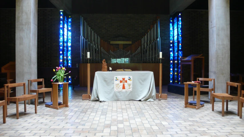 a table and chairs are at a church with a white tablecloth dd over it