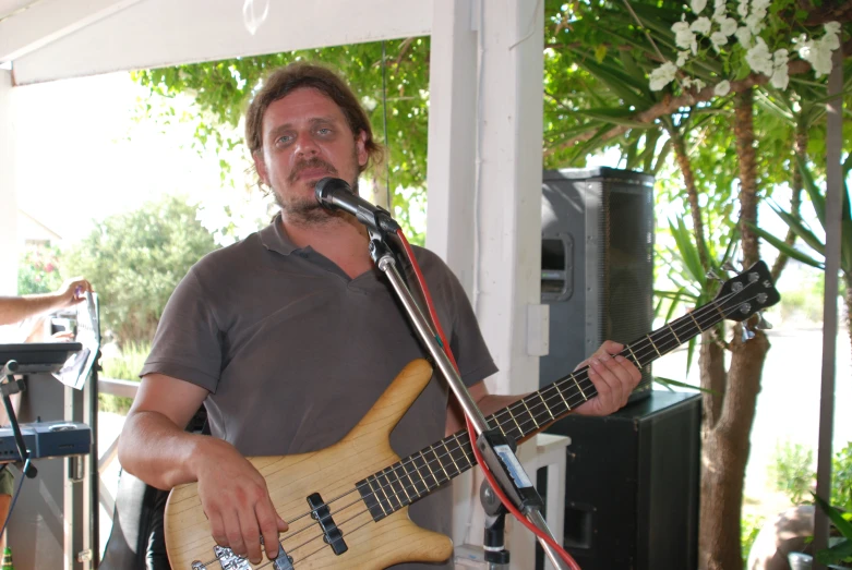 a man standing in front of a microphone holding an electric guitar