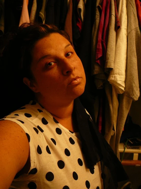 a lady looking off to the side and wearing a white top with black polka dots