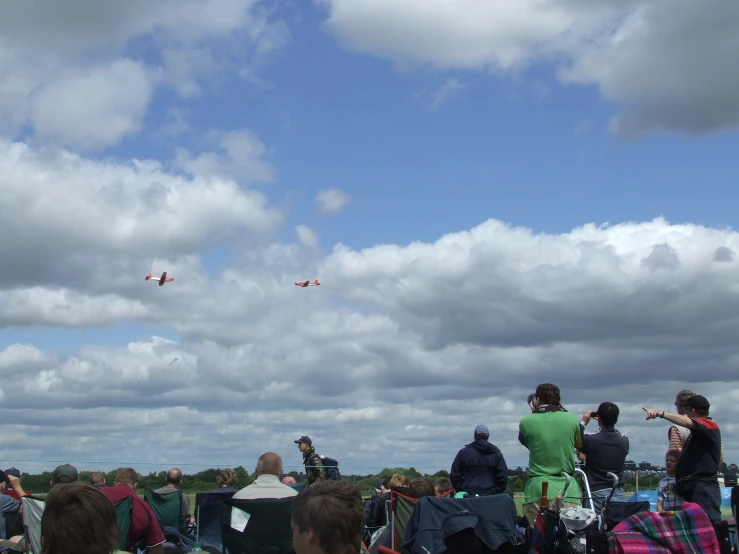 several people watching four airplanes flying overhead