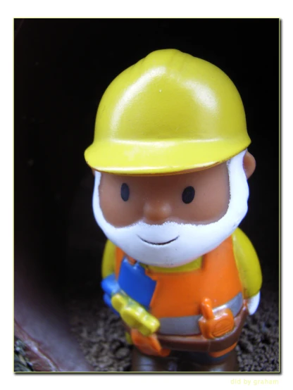 a plastic toy wearing a hard hat and carrying tools