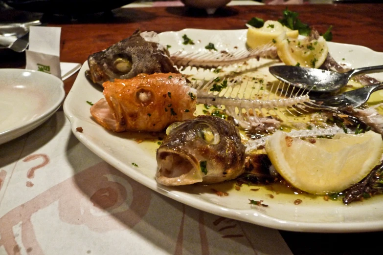 a plate of food that includes fish and a lemon wedge