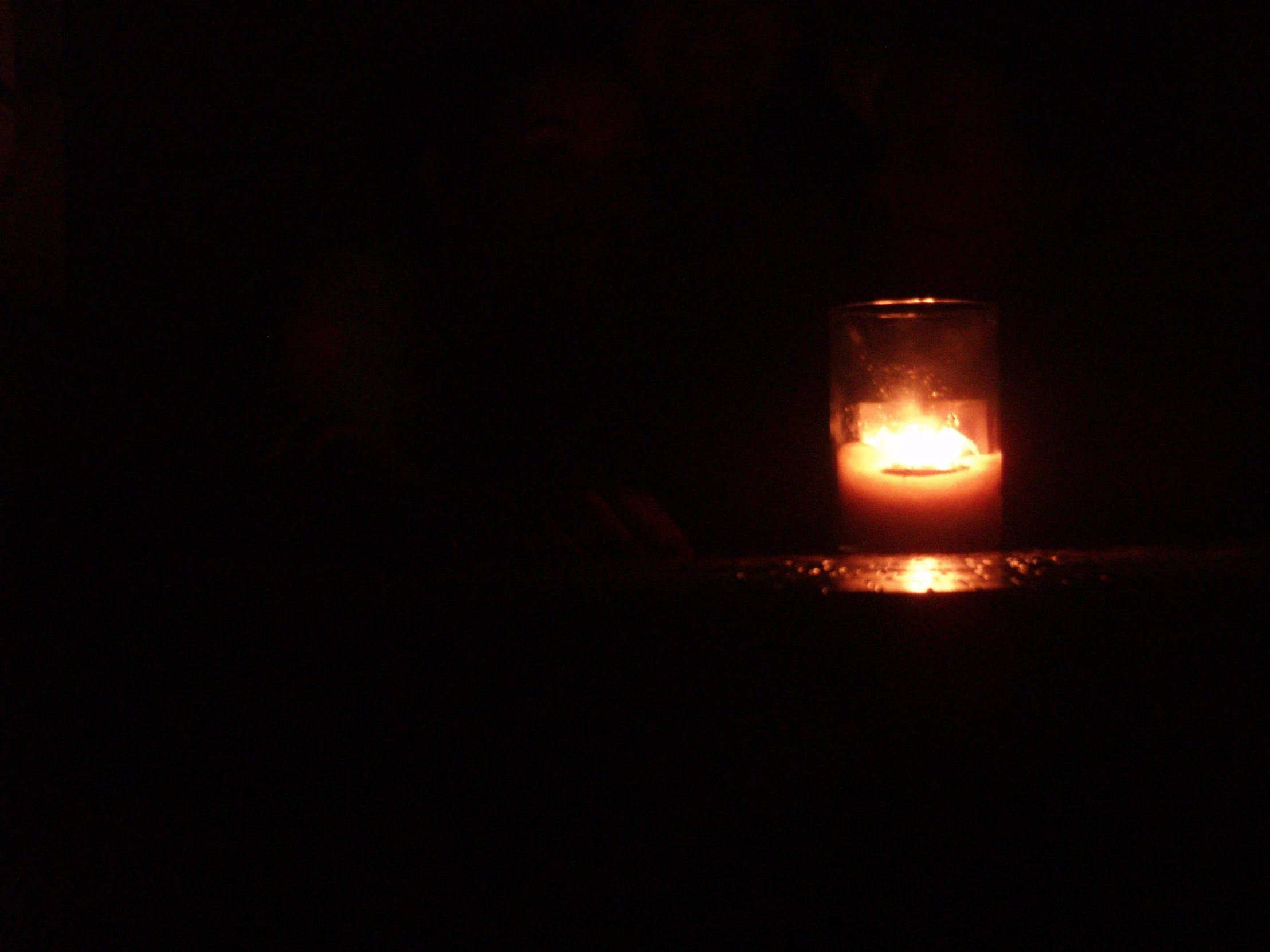 a lit candle is in the dark with a small amount