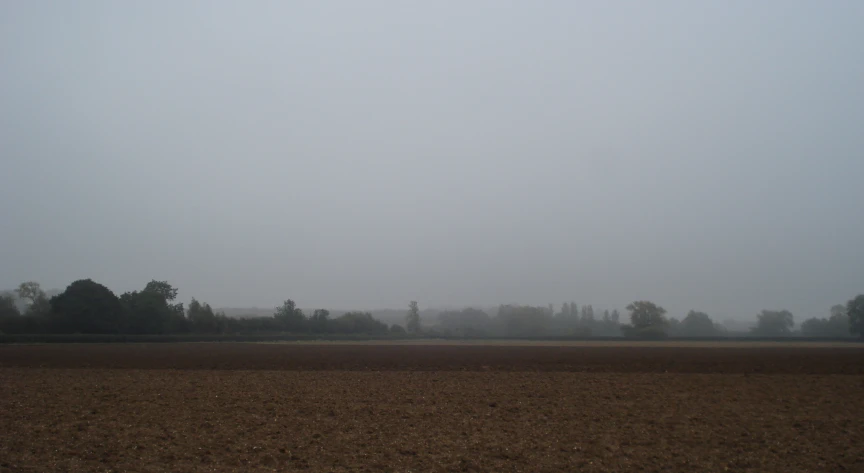 a small airplane flying over an empty field