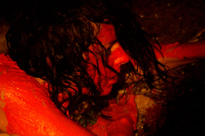 a person covered in red paint and black hair