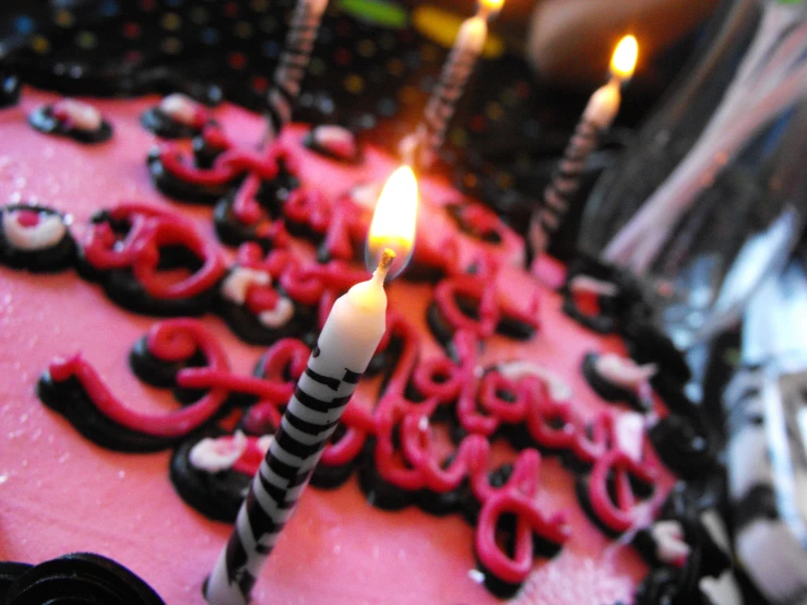 closeup view of some red and black frosted cakes with candles