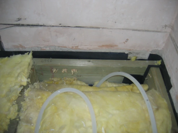 a pile of yellow material sitting in a room with cement and water damage