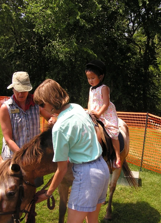 a girl sitting on the back of a horse and another woman holding the horse