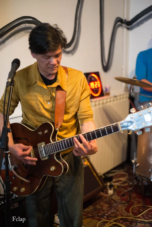 a man with a brown guitar and microphone