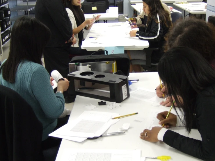 a group of people sitting around tables writing