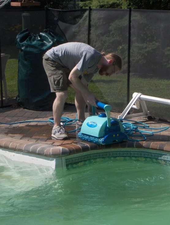 a man wearing a gray shirt is using a small sprayer