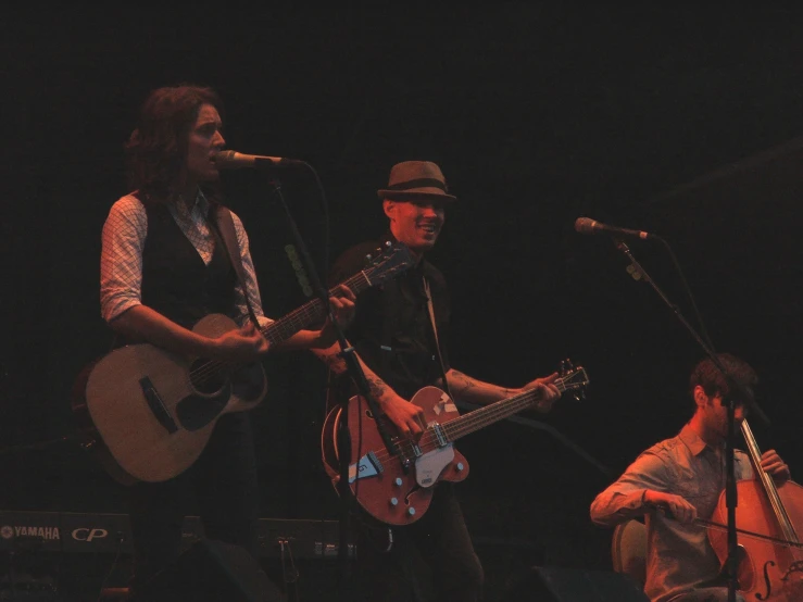 a man singing into a microphone while a woman plays on her guitar