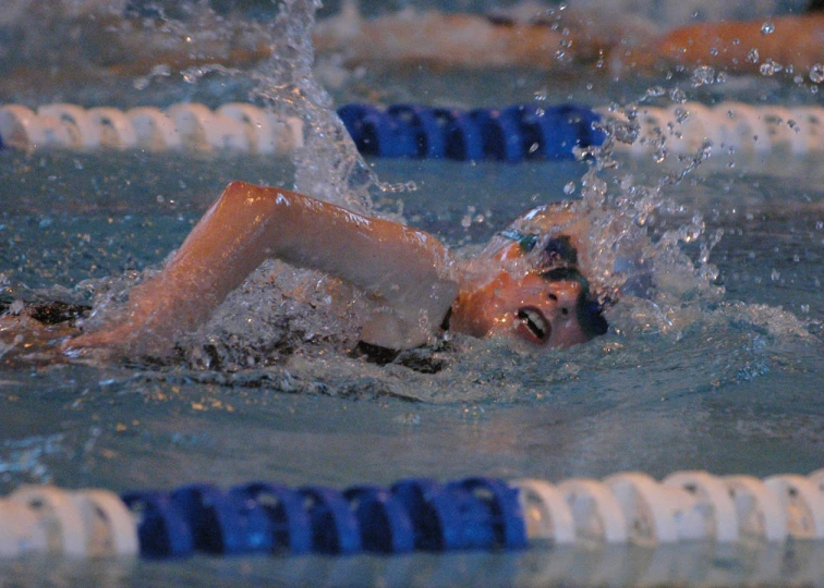 young man swimming in a pool, with water splashing on his face