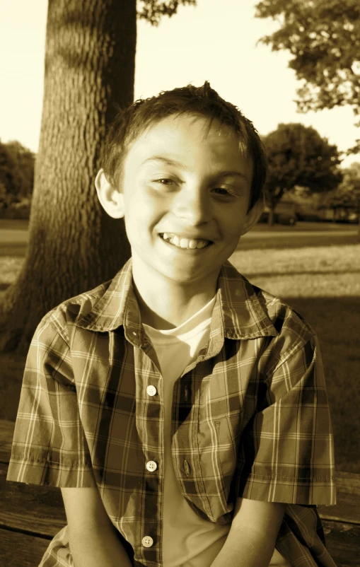 a  smiling and sitting on a bench in front of a tree