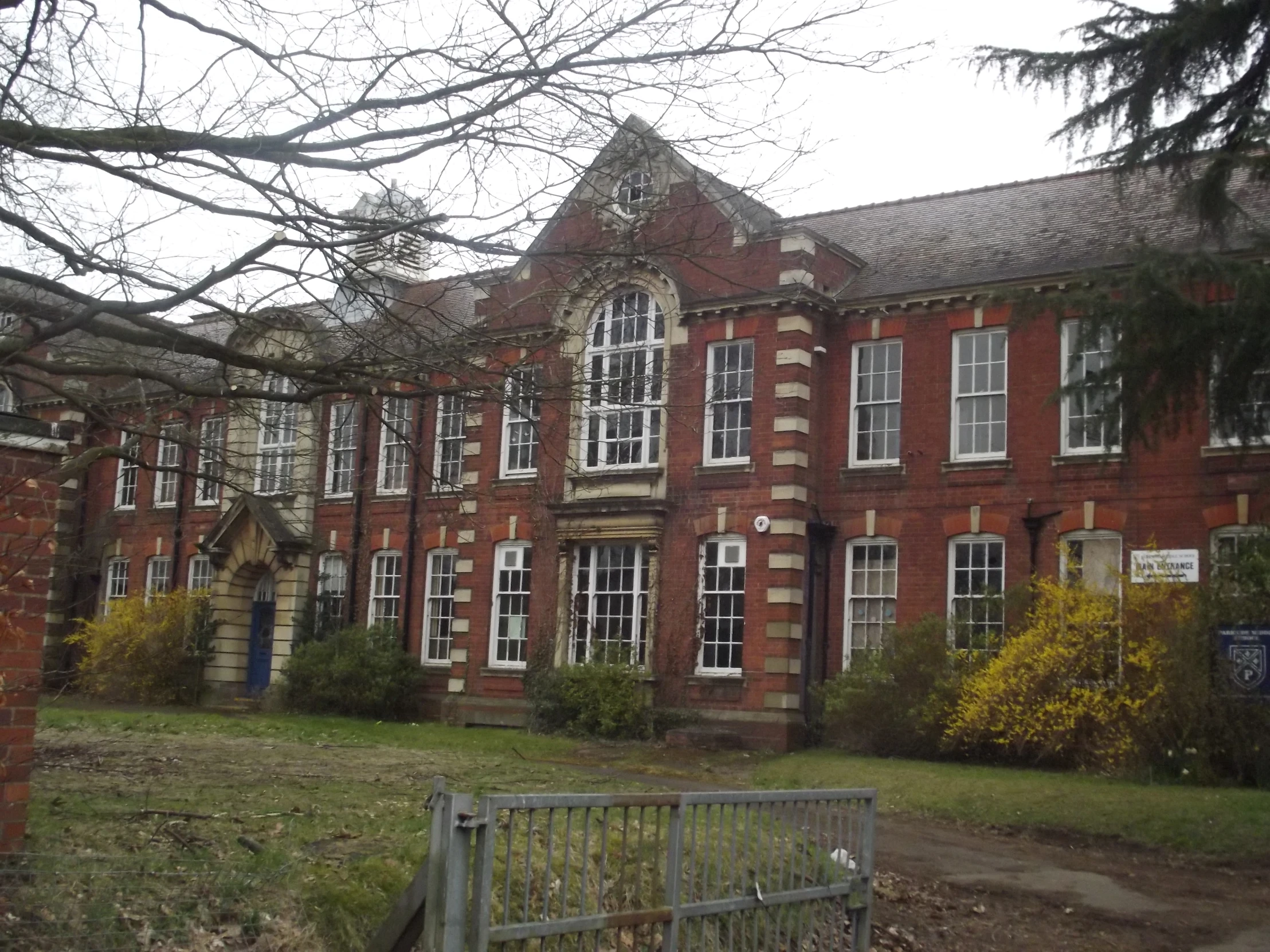 large brick building surrounded by trees and flowers