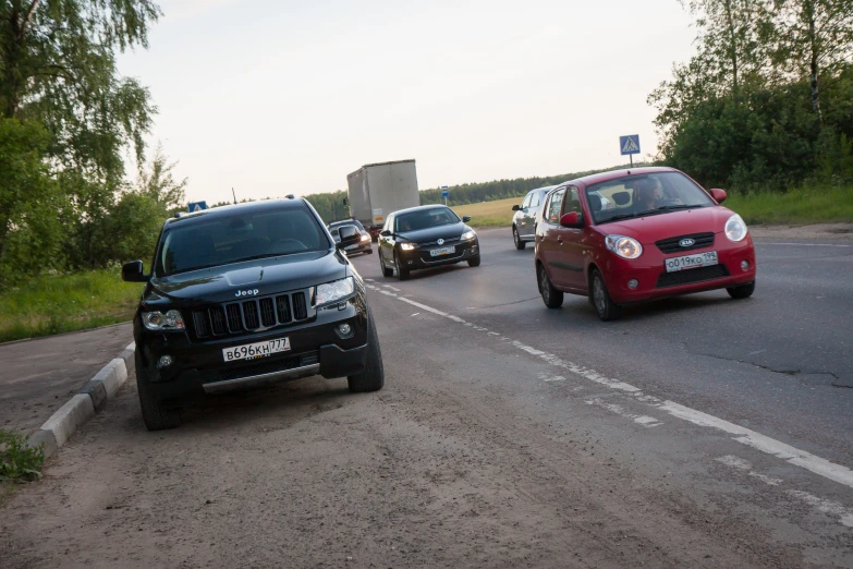 a group of cars and trucks drive down a road