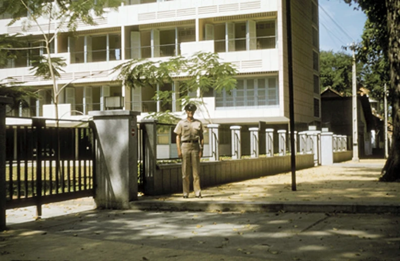 the policeman is standing near a fence in front of the building