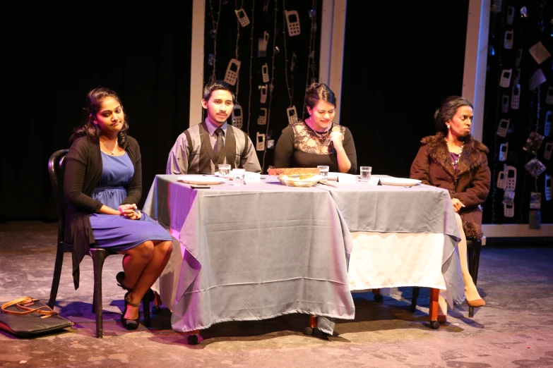 a couple of ladies sitting at a table in front of a person on stage