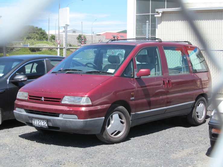 a maroon van with a small black car beside it