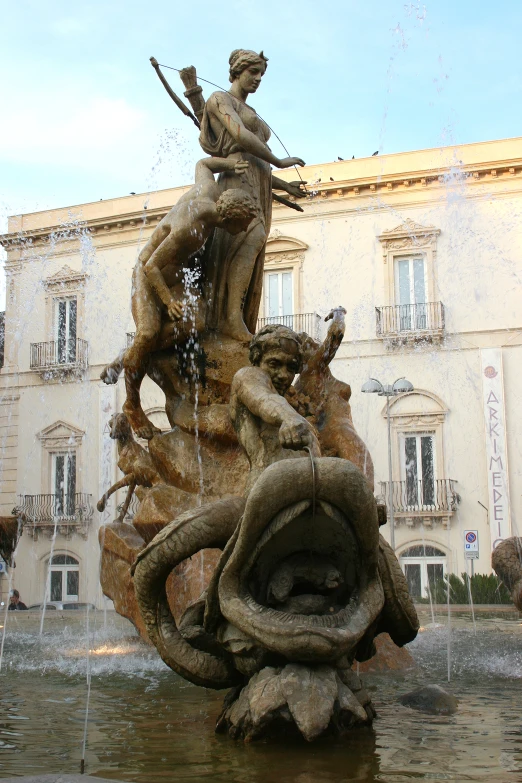 a fountain with a statue in front of a building