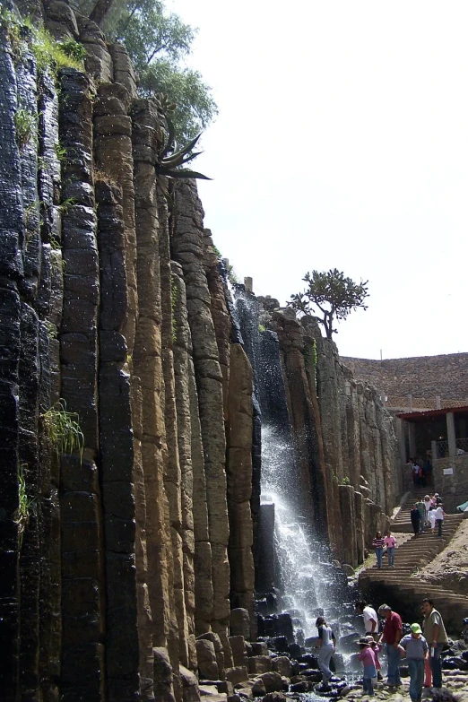 people on the rocks near a waterfall with a sky background