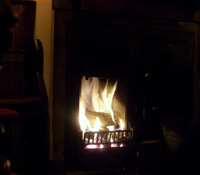 fire burns brightly from a fireplace in a dark room