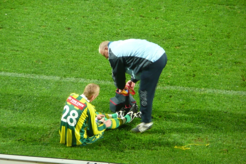 man putting a baby on the foot of a soccer player