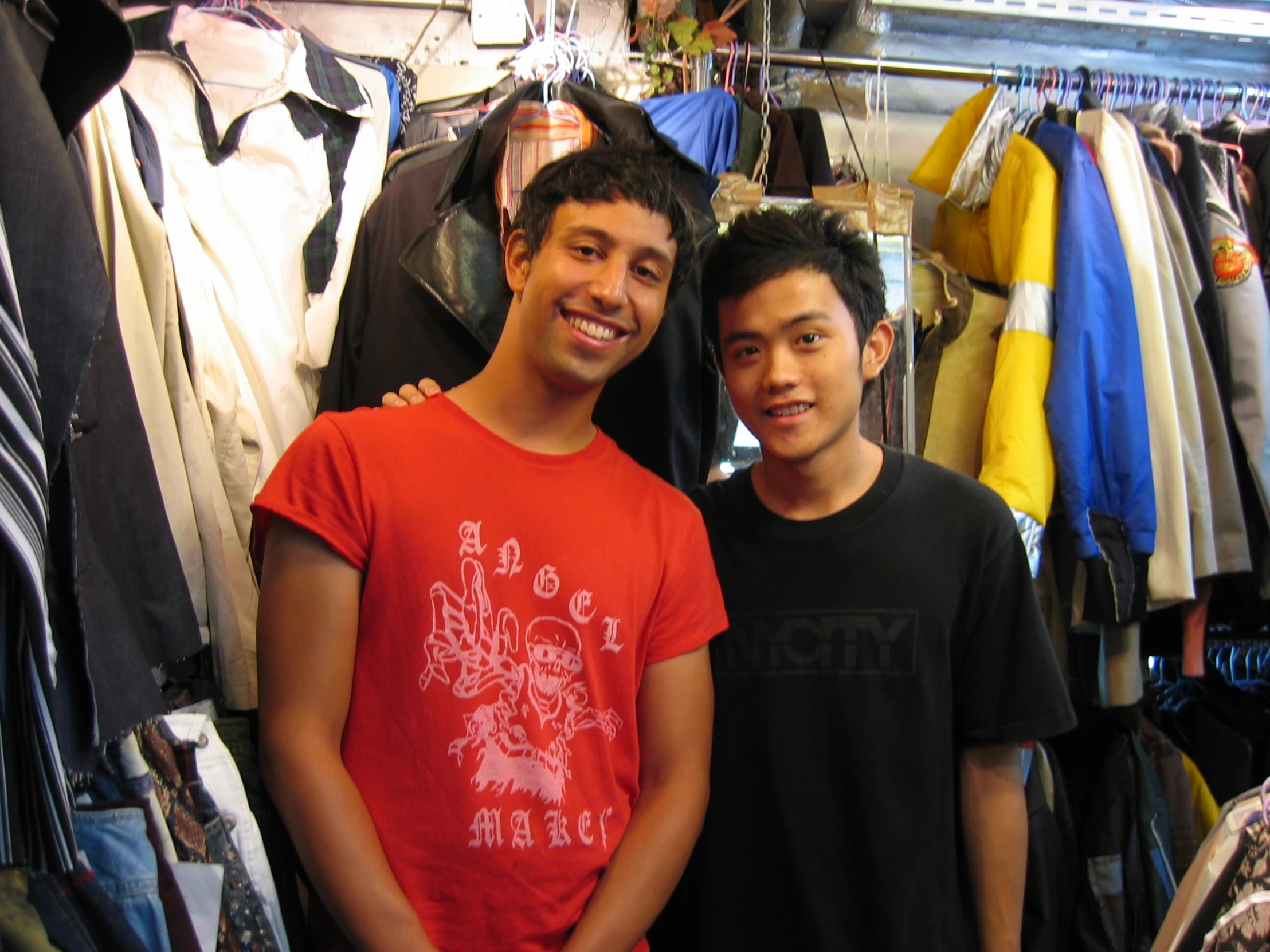 two young men standing in front of several shirts