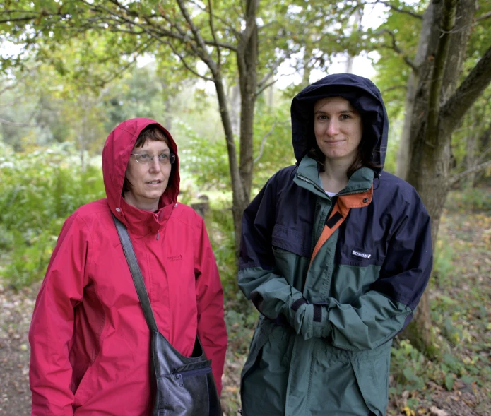 two people standing in the woods in front of trees