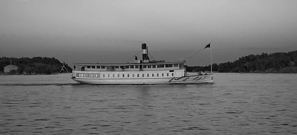 a large white boat on the water in front of some trees