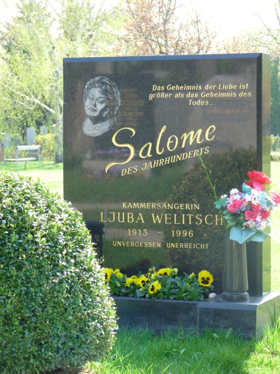 a memorial sign in a field with flowers