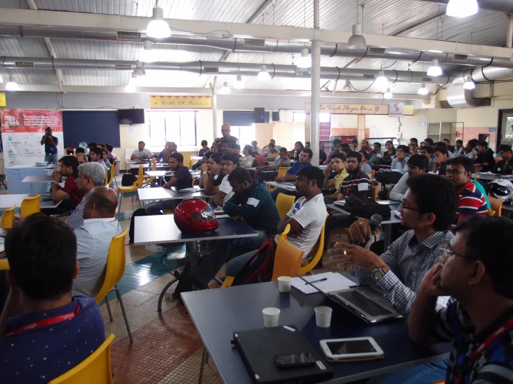 a big room with many people sitting at the tables