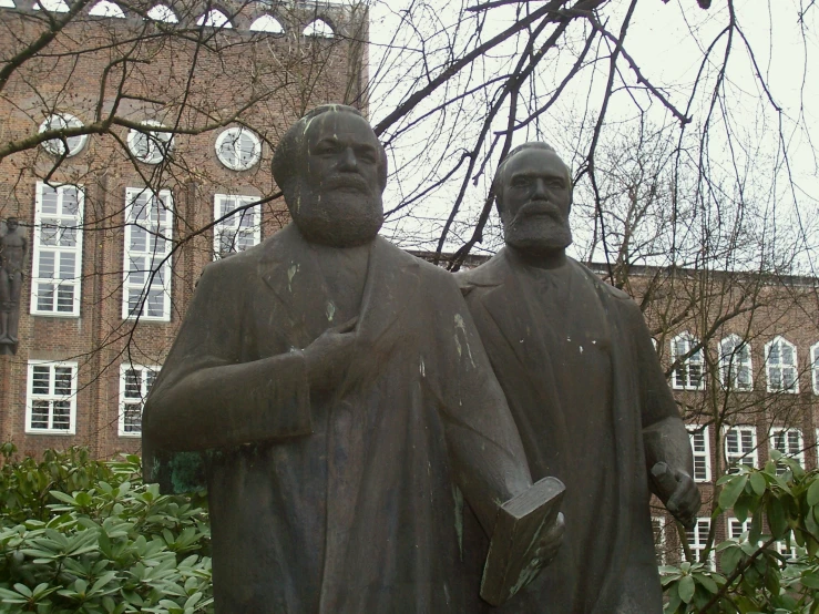 three statue of men in coats with one holding an umbrella