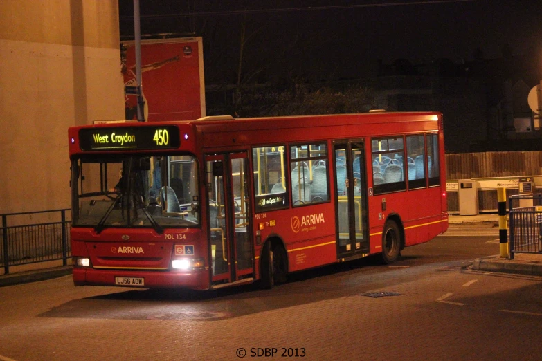 red bus at intersection on empty street at night