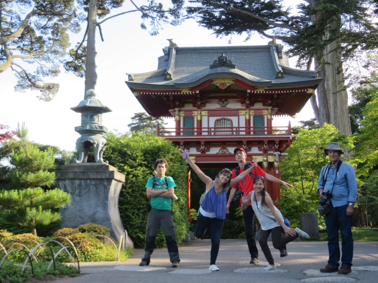 four people standing outside in front of a red structure