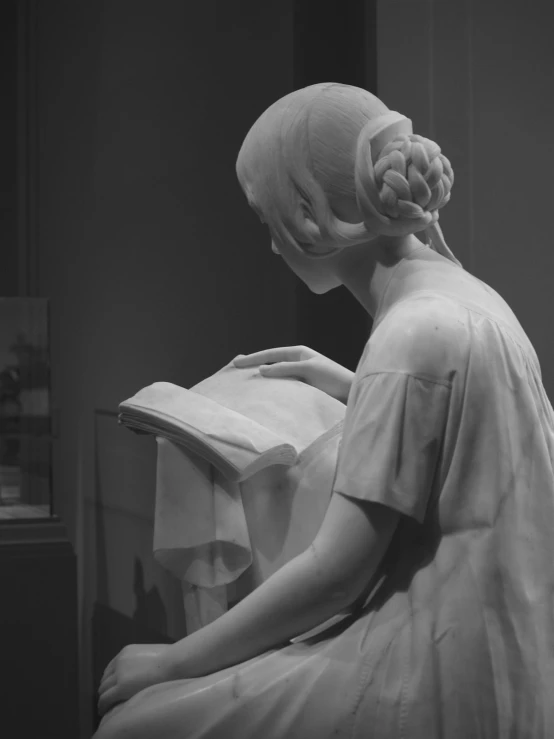 a black and white pograph of a statue with a large book