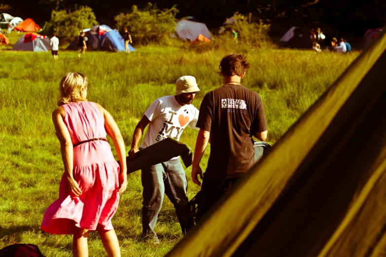 three people standing in a grassy area near tents