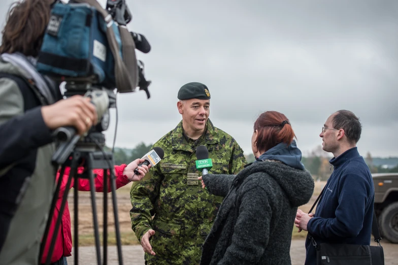 people in camouflage clothing, including a cameraman