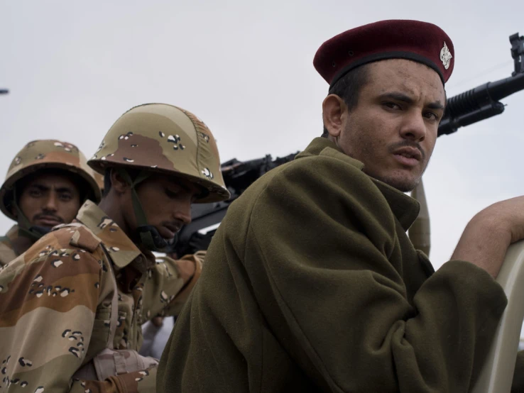 a group of soldiers with helmets on sitting on a vehicle