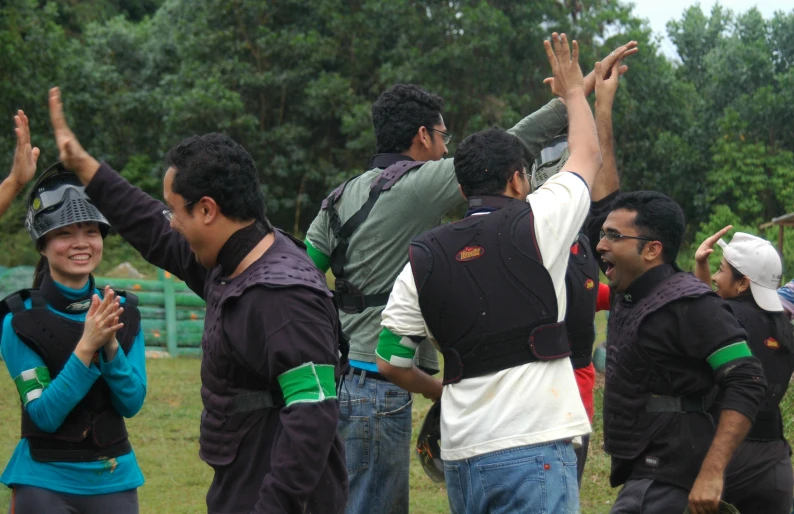 group of people standing around holding their hands up