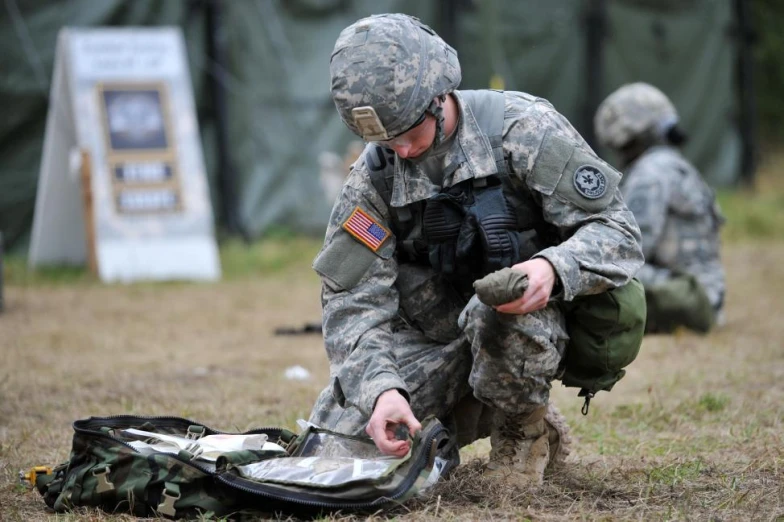 two military soldiers are holding their gear in the field