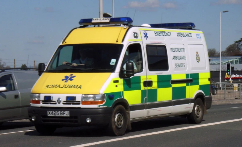 an ambulance with yellow, green and white plaid parked in traffic