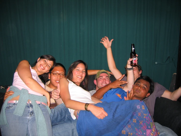 a group of people all laying down on a bed holding a beer