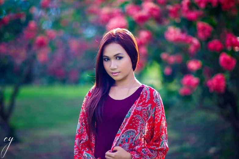 an attractive young woman standing in front of flowers