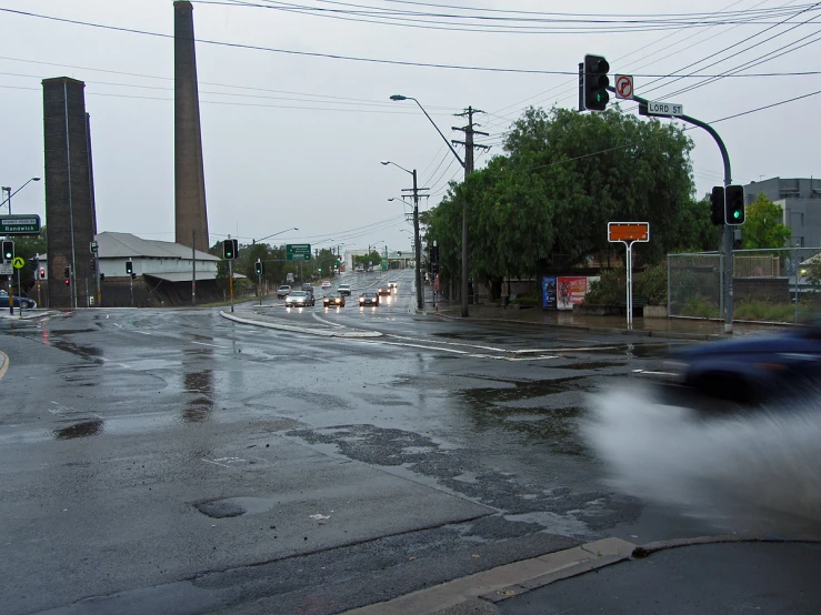 cars travelling on the rain soaked road near a building