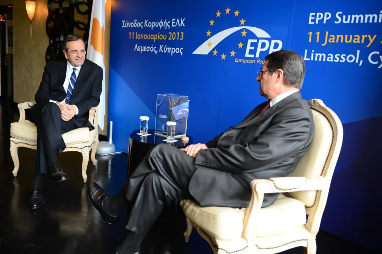 two men sitting in chairs and speaking to each other