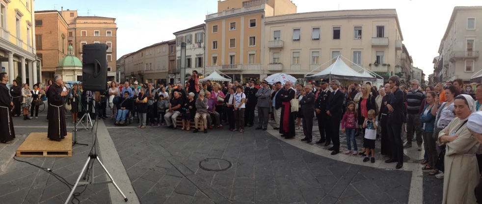 a crowd of people standing around a street in front of a speaker