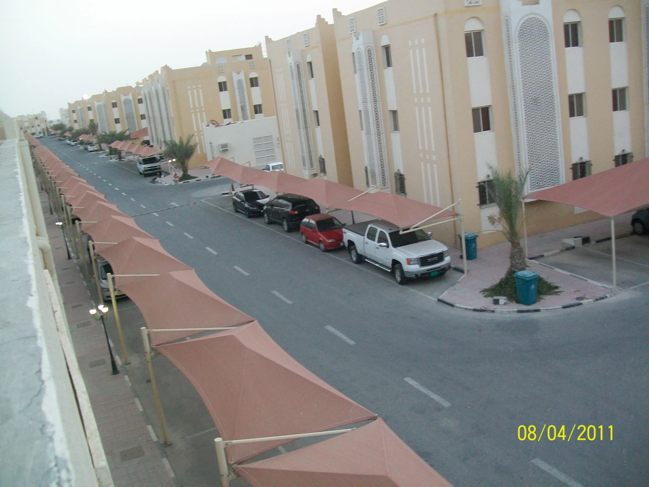 cars parked along an empty street with a pink awning