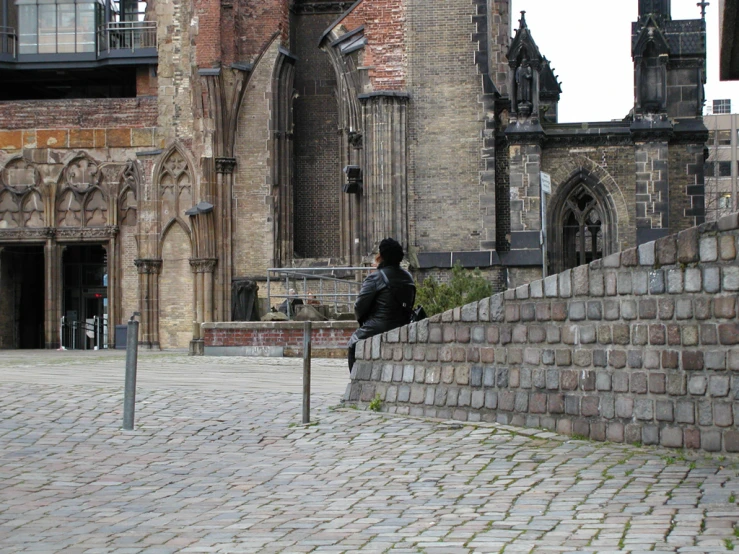 a person is sitting on a wall near a cathedral